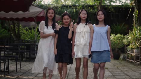 four teen girls walking together in a garden cafe