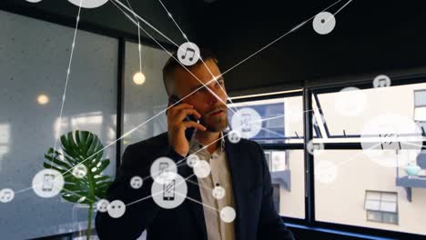network of digital icons against caucasian businessman talking on smartphone at office