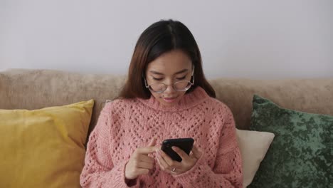 middle eastern young female sitting on the sofa in the living room with a smartphone and buying online in the internet supermarket, online, delivery, food, order. cell gadget technology