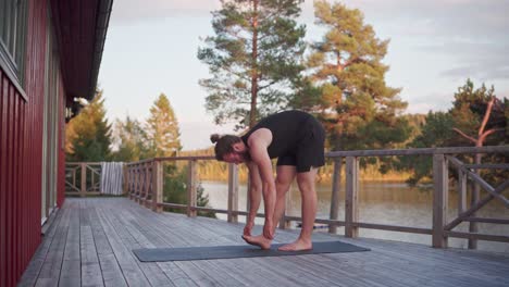 Joven-Haciendo-Un-Estiramiento-De-Flexión-Hacia-Adelante-En-Una-Alfombra-De-Yoga