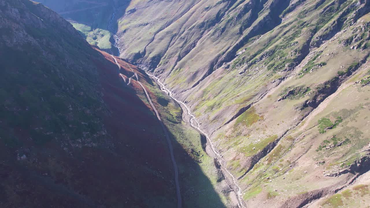 Drone tilt-up reveals a steep-sided valley with rugged slopes and winding stream. Sharda, Neelum Valley, Kashmir