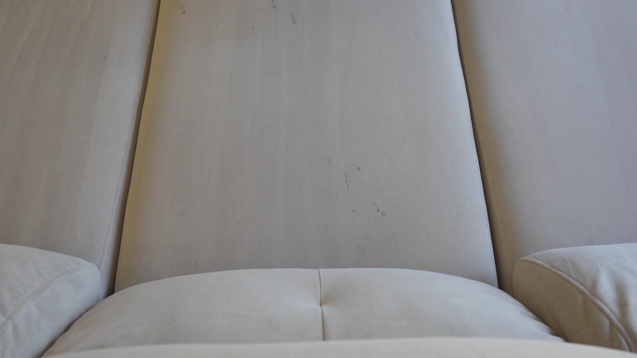 Top down view of a sofa seat and the nozzle of a pressure washer appearing to clean it and eliminate germs and bacteria without damaging the sofa due to the ionized water