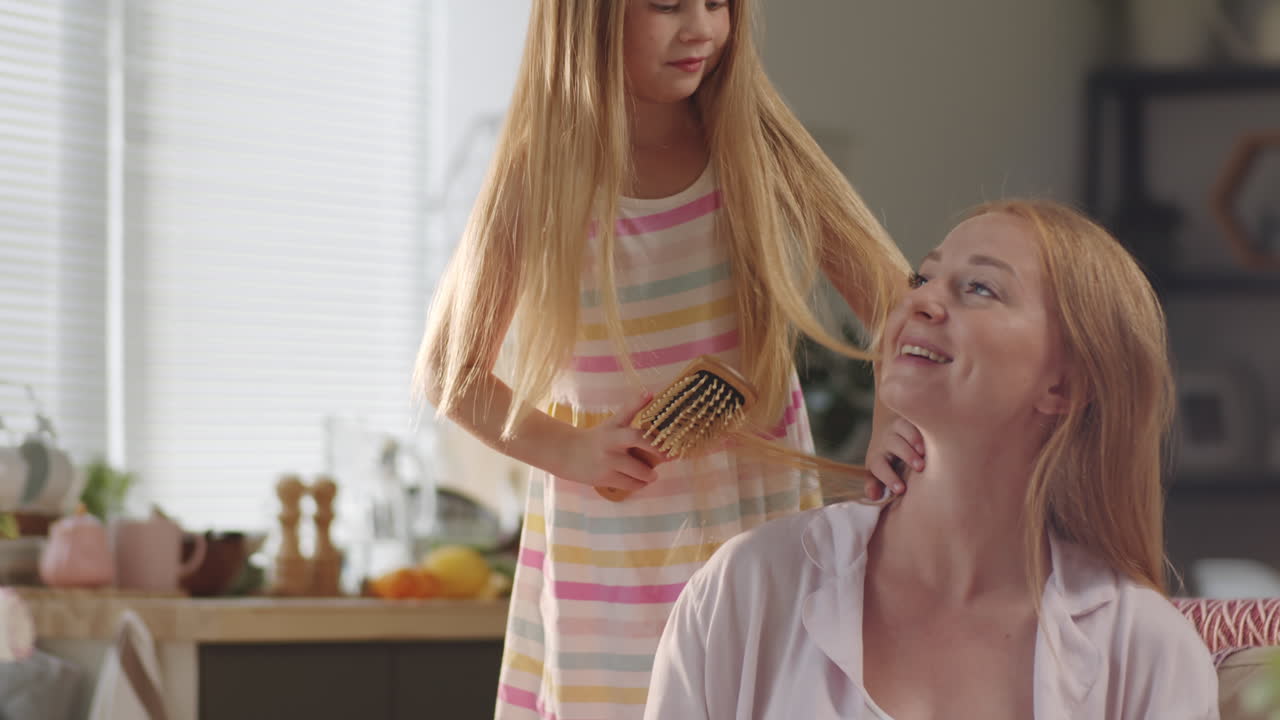 집에서 어머니의 머리카락을 는 어린 소녀