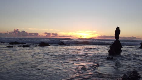 Stunning-view-of-the-sunset-at-low-tide-in-Laguna-Beach-as-the-sun-peaks-out-amongst-rocks-and-reflects-off-the-water