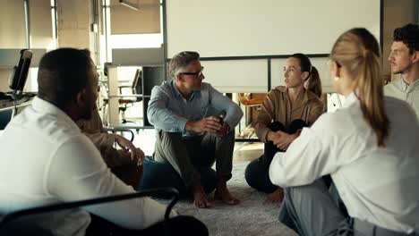 Gruppentherapie:-Menschen-In-Geschäftsanzügen-Kommunizieren-Untereinander,-Während-Sie-Im-Büro-Auf-Einer-Matte-Sitzen