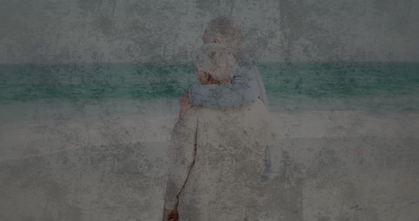 Uomo che porta in braccio la partner, si muove per osservare l'oceano, calpestando la sabbia, con un effetto di grana che ammorbidisce la scena di viaggio