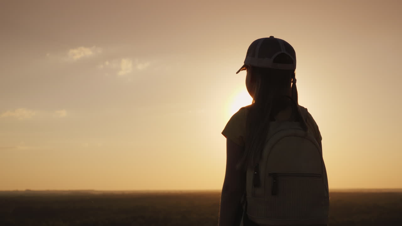 девушка с рюкзаком находится в живописном месте, с нетерпением ожидая заката маленький путешественник и