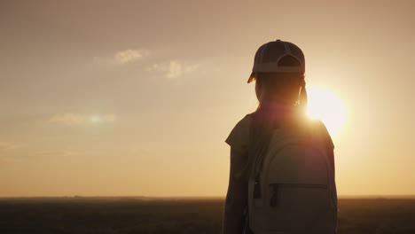 una chica con una mochila está en un lugar pintoresco esperando la puesta de sol un pequeño viajero y