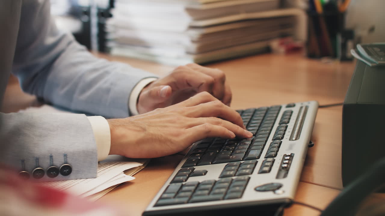 Un giovane lavora al portatile seduto a un tavolo nel suo ufficio domestico alla ricerca dei nodi informativi necessari e