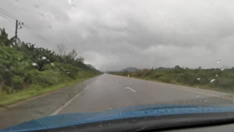 tiempo tormentoso con fuertes lluvias conduciendo a lo largo de una larga carretera rural recta en tailandia