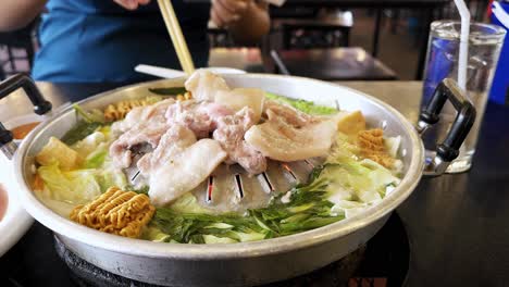 Traditional-grill-pork-BBQ-Thai-style-grilling-with-vegetables-on-the-brass-pan-and-delicious-soup-in-buffet-restaurant-at-dinner