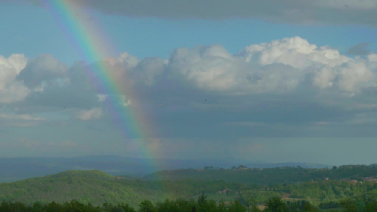 arco iris que termina su carrera en medio de los árboles de una colina en chianti. montepulciano