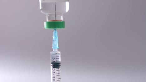 Close-up-of-insulin-vial-and-syringe-on-grey-background-with-copy-space,-slow-motion