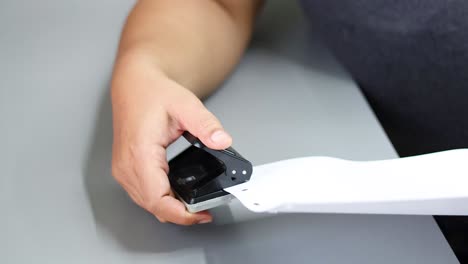 person using a hole punch on a strip of paper.