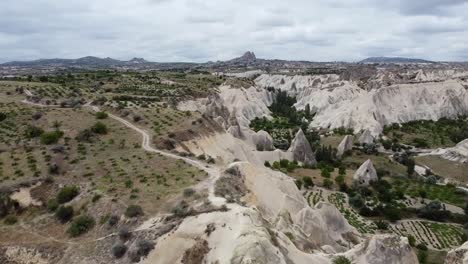 Drone-aerial-view-of-Love-Valley-landscape-in-Cappadocia,-Turkey,-with-the-village-of-Uchisar-and-rock-formations