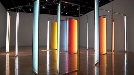 large. vibrant panels. encased in metal frames. stand in a gallery space. their colors transitioning from one shade to another. creating a modern art installation that reflects in the polished floor