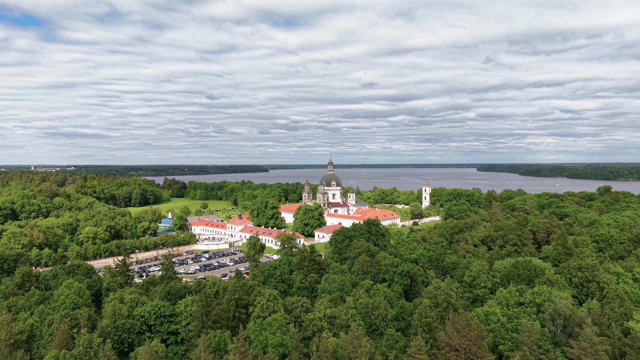 Fantastiske flybilder av Pazaislis-klosteret som ligger i en tett grønn skog ved Kaunas-reservoaret, Litauen. Dramatiske skyer, bred landskapskomposisjon, naturlig dagslys, ingen mennesker synlige