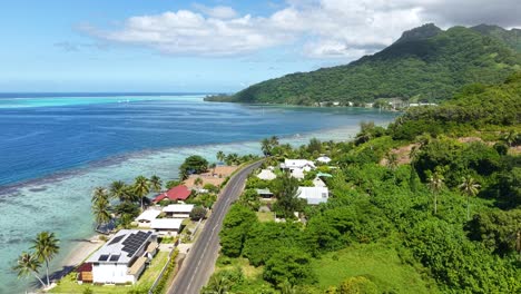 moorea, french polynesia. establishing drone shot of island coastline, lagoon, coral reefs, road and waterfront homes