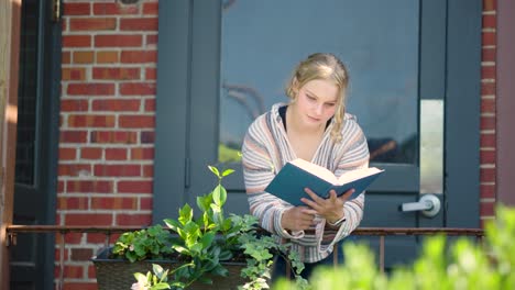 Girl-student-reading-book-over-a-side-rail-outside-of-a-door