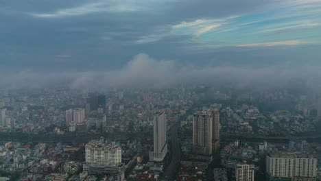 Am-Frühen-Morgen-Umkreist-Der-Städtische-Drohnenflug-Hochhäuser-Und-Hauptstraßen-Und-Brücken-Mit-Dichtem-Nebel-Und-Niedrigen-Wolken-Im-Uhrzeigersinn