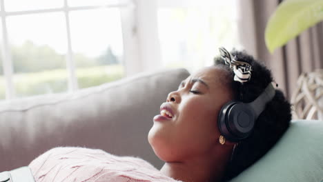 african american woman enjoys music on headphones, eyes closed, at home