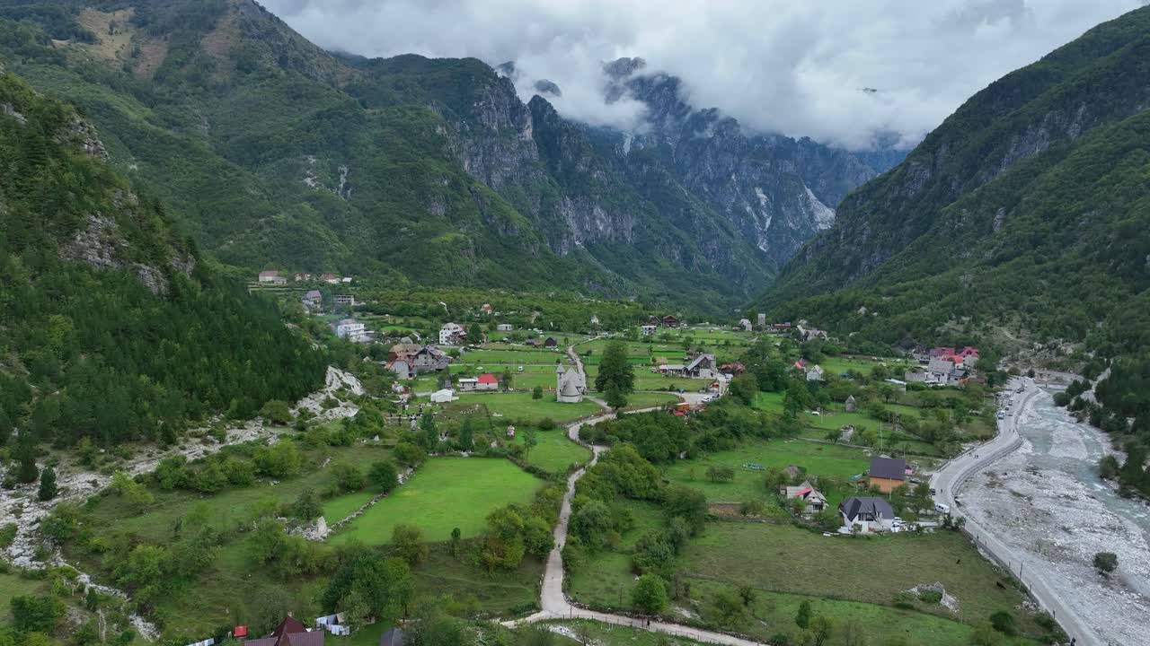 Village of Theth by green mountains in Albania, wide forward aerial
