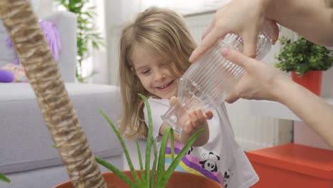 mother and daughter water the flowers in their house.