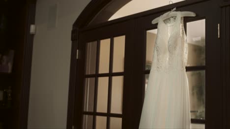 hanging wedding dress on door wide shot