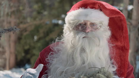 le père noël tient un sac en plastique plein de mousse et parle à la caméra