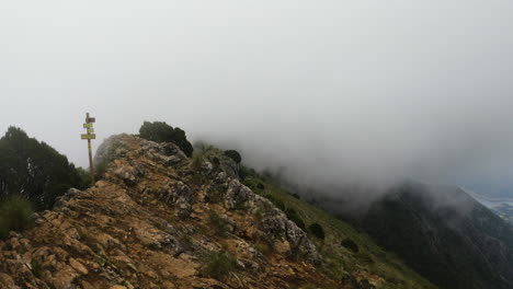 4k-Static-shot-of-fog-and-clouds-around-a-mountain-ridge-with-a-hiking-sign