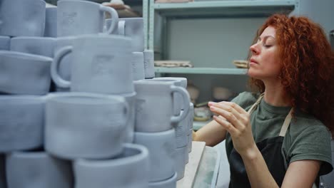 woman inspecting handmade pottery mugs