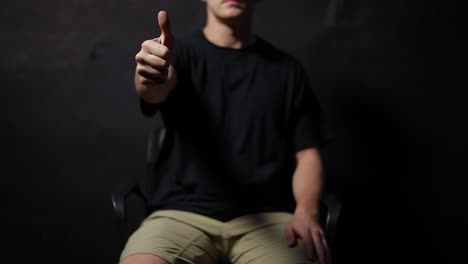 Shot-of-a-man-sitting-on-a-chair-and-giving-an-enthusiastic-thumbs-up-sign-with-his-hands