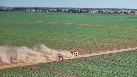 Large-clouds-of-dust-come-off-a-tractor-pulling-a-small-road-grader-on-dirt-road