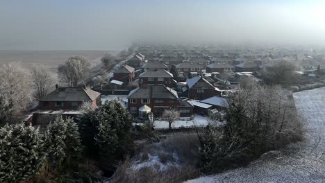 aerial view across small town houses in england with frosty morning fog on the horizon