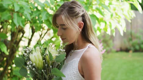 happy caucasian woman holding bunch of flowers in garden on sunny day