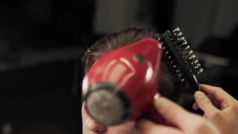 male hands of the master of a haircut put long hair by the hair dryer