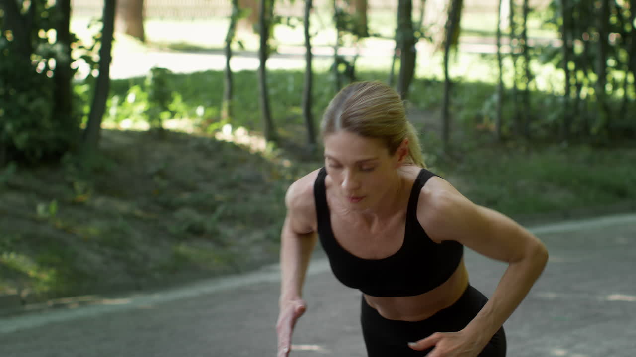 A woman in sportswear prepares for a run in a park