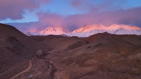 volando sobre las colinas de tungsteno al amanecer mirando a la cordillera de la sierra nevada con nubes rosadas