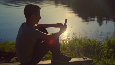 teenager taking a selfie by a lake at sunset