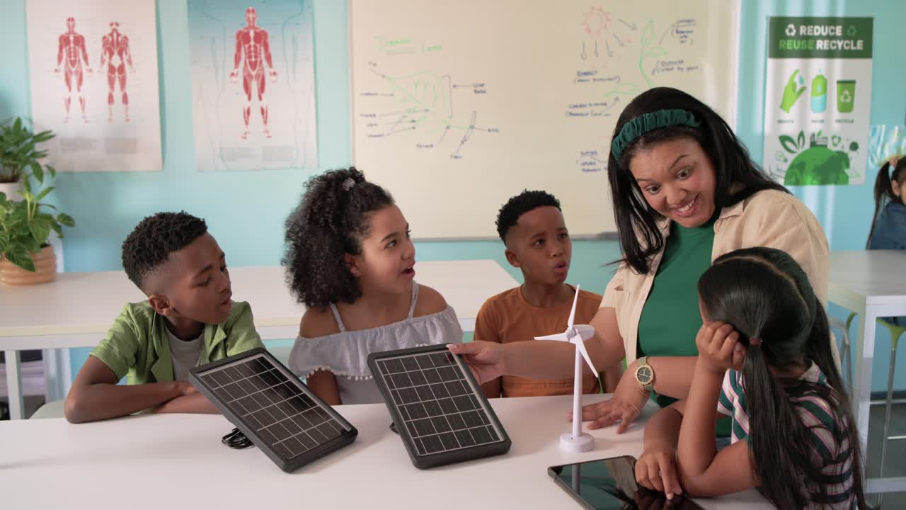 African American teacher leading STEM demo with kids at table tapping solar panels to link turbine