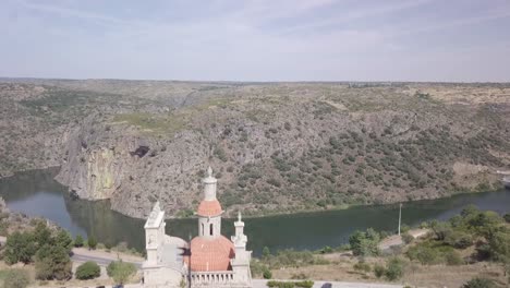 Reveal-drone-shot-of-River-behind-Medieval-European-Church