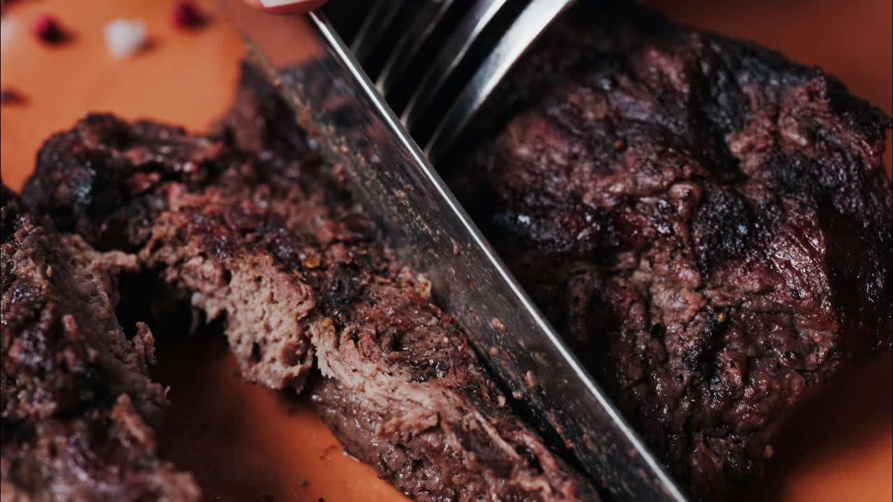 Close up of a woman's hands cutting a Sirloin Steak with Barbecue Sauce and micro-plants on the side