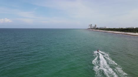 Aerial-view-of-Surfside-Beach,-Miami-as-jetski-enters-frame-from-below