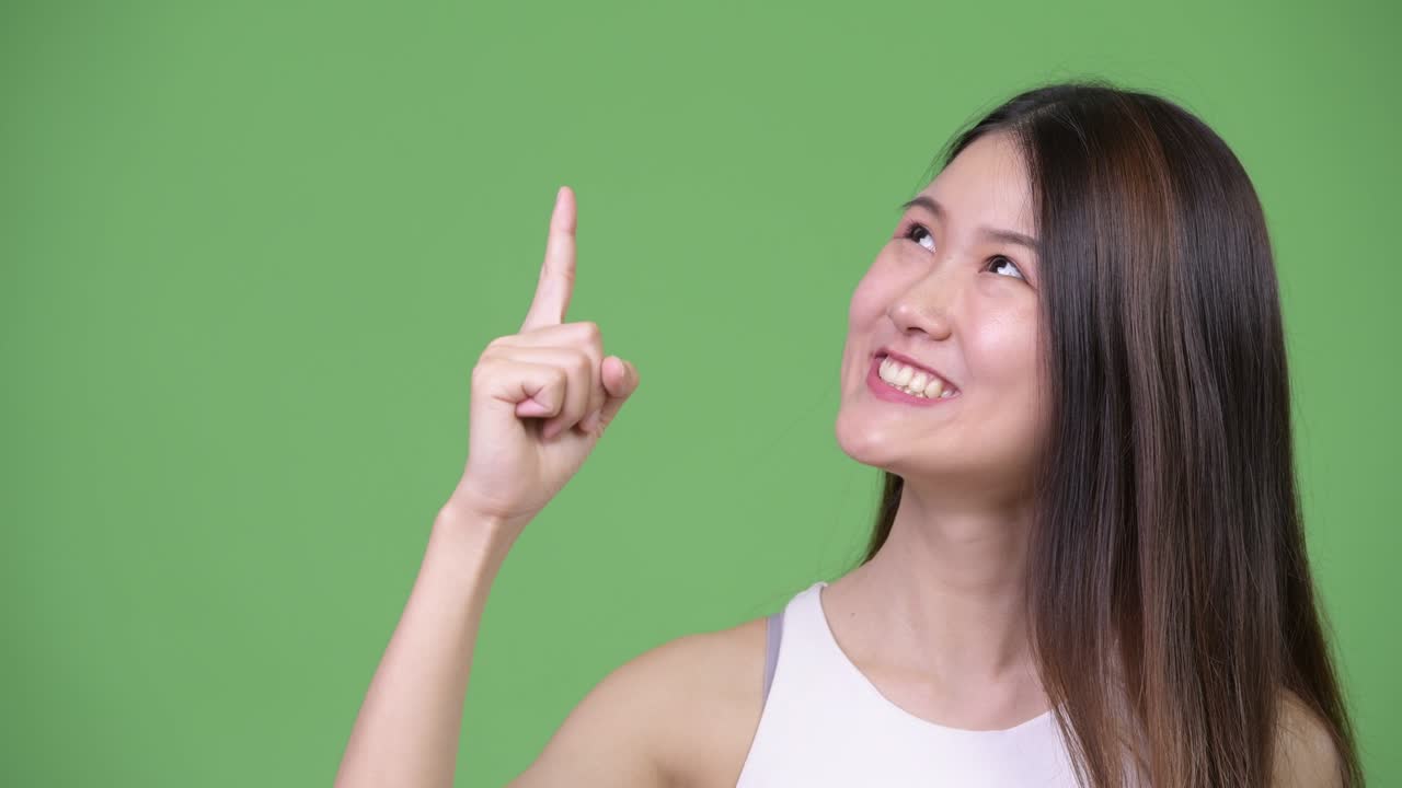 젊은 아름다운 아시아 사업가 여성이 위를 가리키고 있습니다.