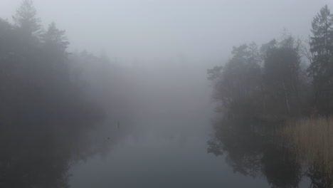 dolly in of beautiful mist covered lake surrounded by forest