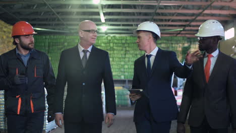 business professionals and workers discussing operations in a warehouse