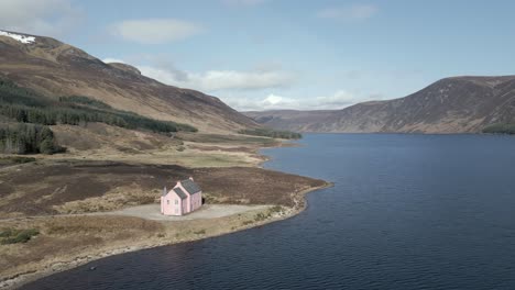 aerial view of the famous pink house on the shores of loch glass in the scottish highlands on a sunny spring day