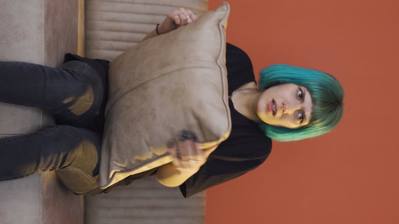 Vertical video of The young woman who presses the pillows on her head with fear.