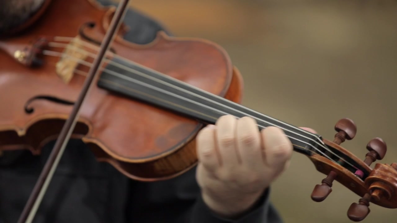 Close up to the hands of an artist playing a beautiful violin in an elegant and professional way
