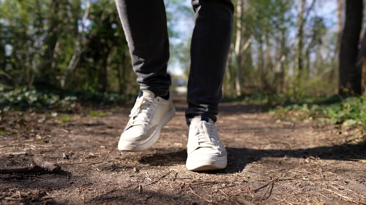 cerrar a pie de hombre con zapatos blancos, caminar por senderos en el bosque